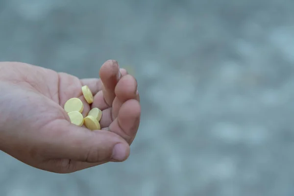 Желтая круглая таблетка в грязных руках детей — стоковое фото