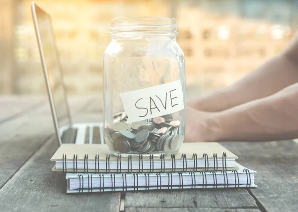 Money for saving in glass jar on note book and laptop — Stock Photo, Image