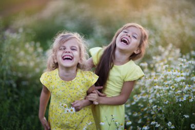 Papatya tarlasında gülen iki küçük kız