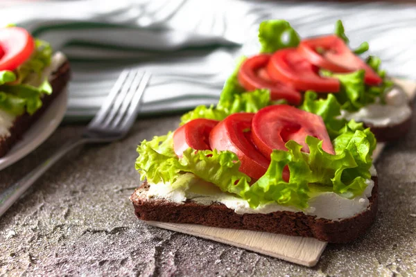三明治三明治 有奶油奶酪 西红柿和生菜在木板上的黑面包和水泥背景的亚麻布毛巾 健康的小吃早餐 — 图库照片