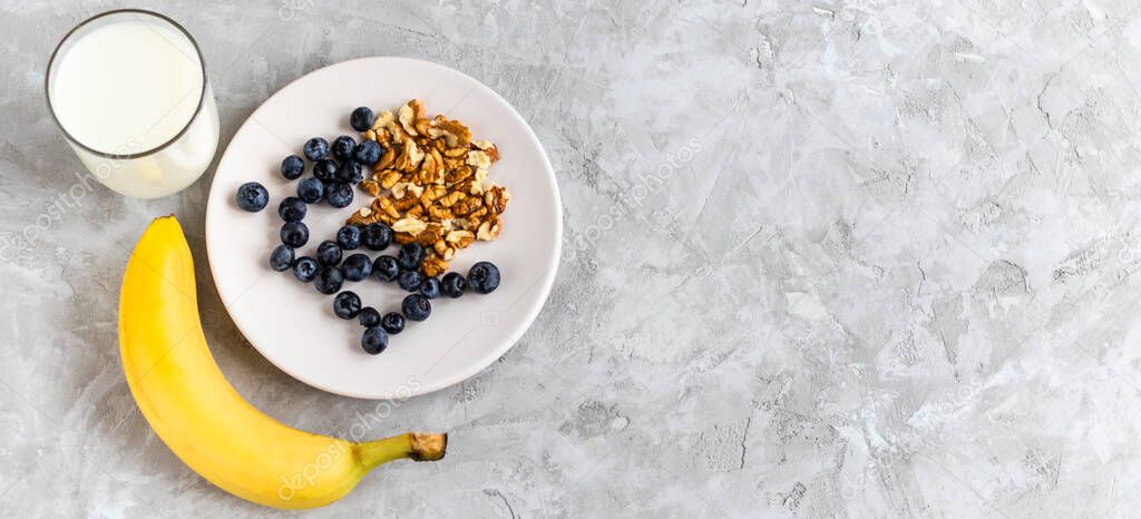 Healthy breakfast, blueberry, walnut, banana, glass of milk on cement background. healthy food. Proper nutrition