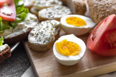 Sağlıklı atıştırmalık ve öğle yemeği için yumurta ve dilek kes. Haşlanmış yumurta, krem peynirli sandviç, domates, ahşap tahtada marul. Yerleşim kararı yakın plan