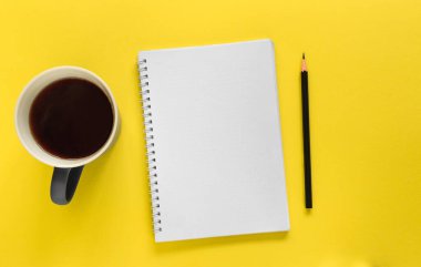 Sarı arka planda defter, kalem ve fincan kahve (çay). Liste yapmak için. Fotokopi alanı olan düz dizayn.