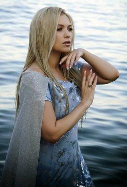 Güzel kız sahilde suyun içinde duruyor.       