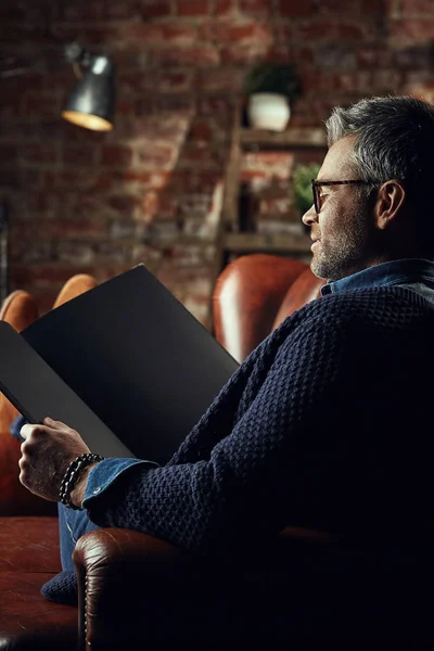 Стильный мужчина с седыми волосами на чердаке студии с книгой в руках — стоковое фото
