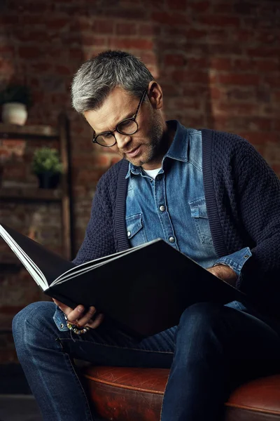 Retrato del hombre guapo con el pelo gris en el estudio loft leyendo un libro — Foto de Stock
