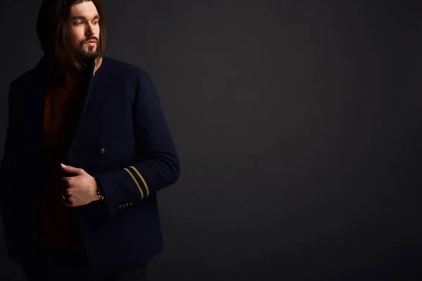 Bello serio modello maschile moderno in studio scuro in giacca — Foto Stock