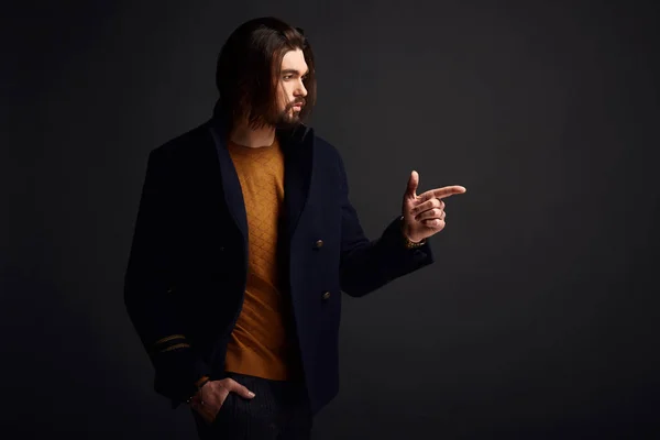 Красивий стильний чоловік з довгим волоссям у темній студії в синій куртці — стокове фото