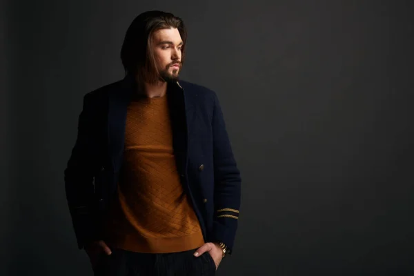 Attraktiva eleganta mannen med långt hår i mörka studio bär blå jacka — Stockfoto