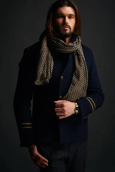 Attraente uomo elegante con i capelli lunghi in studio scuro indossa giacca blu classico — Foto Stock