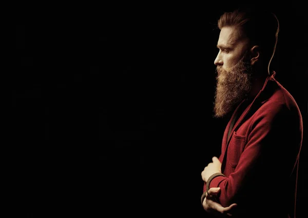 Красивий чоловік з бородою в темній студії в куртці — стокове фото