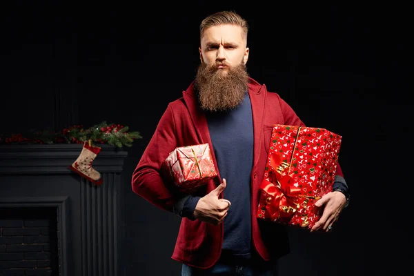 Handsome serious man with long beard with red christmas boxes in his hands — Stock Photo, Image