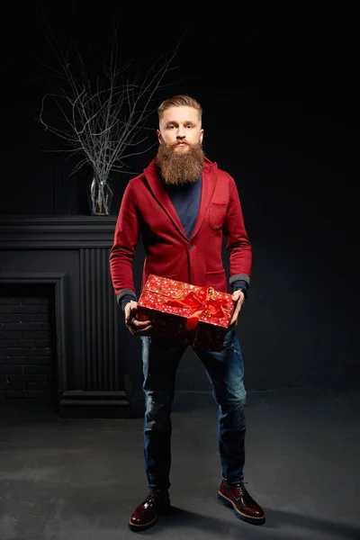 Modelo atraente macho com barba no estúdio escuro vestindo casaco vermelho — Fotografia de Stock