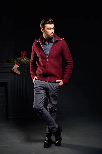 在工作室与圣诞袜子背景穿红色夹克的严重时尚男人 — 图库照片