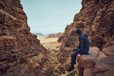 Orta yaş erkek kara giysili Wadi Rum çölde Ürdün kırmızı kayanın üzerine oturmuş