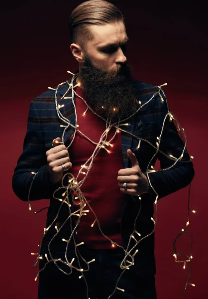 Portrait of serious handsome man with beard and christmas garland in studio — Stok Foto