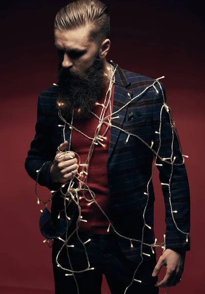 Porträt eines ernst zu nehmenden gutaussehenden Mannes mit Bart und Weihnachtsbeleuchtung an sich selbst im Studio — Stockfoto