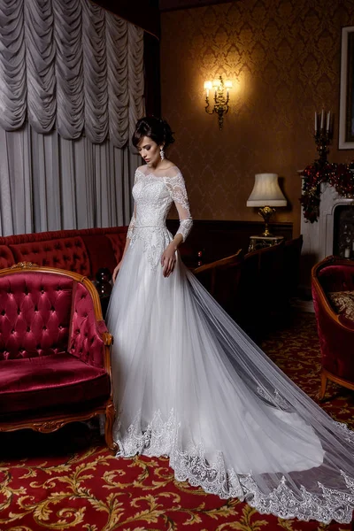 Young model in charming long bridal dress with lace on glamour background — Stock Photo, Image