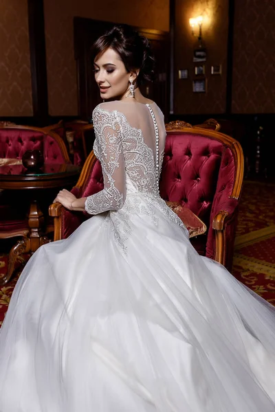 Giovane modello posa in affascinante abito da sposa lungo con pizzo su sfondo elegante — Foto Stock