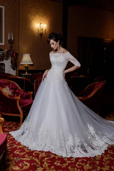 Young model poses in charming long bridal dress with lace on fashion background — Stock Photo, Image