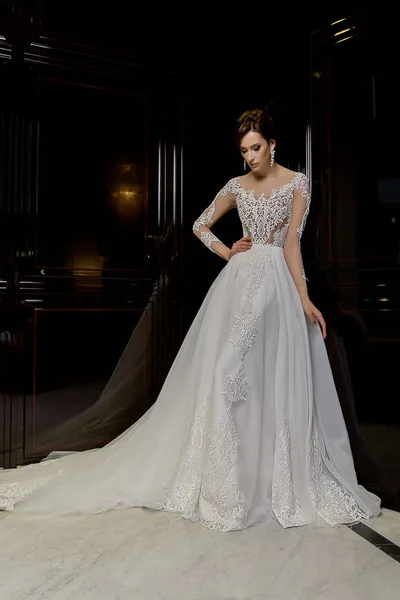 Schattige jonge brunette model poses in lang bruids jurk met kant op mode achtergrond — Stockfoto