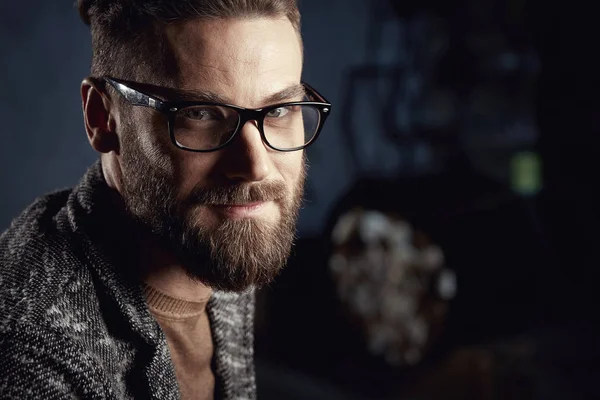 Retrato de close-up de belo jovem sorridente com barba em óculos no fundo escuro — Fotografia de Stock