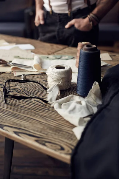 Wooden table with treads and other tailoring equipment in atelier