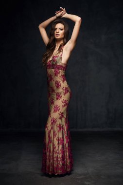 Güzel genç seksi model erkek şaşırtıcı uzun bej elbise ve siyah ayakkabı karanlık Studio'da poz koyu saçlı