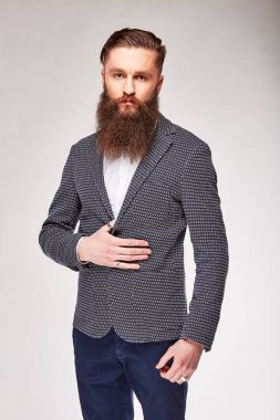 Genç adam stüdyo ışık gri trendy ceket, beyaz gömlek ve Mavi pantolon poz sakallı