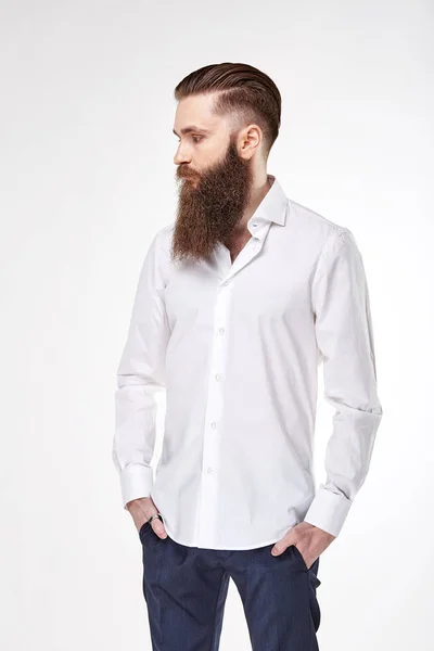 Young bearded man posing in studio in trendy white shirt and blue pants — Stock Photo, Image