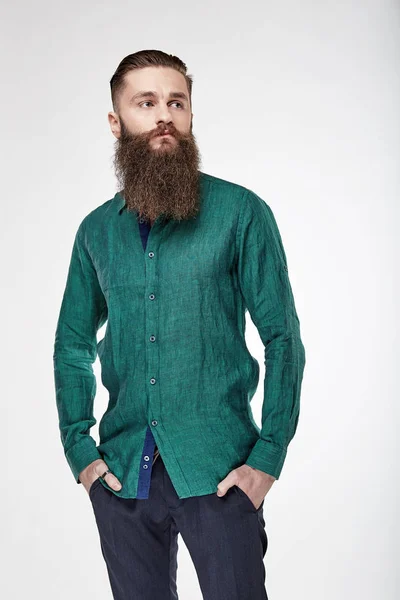 Joven hombre barbudo posando en estudio en lino de moda camisa verde profundo y pantalones azules —  Fotos de Stock