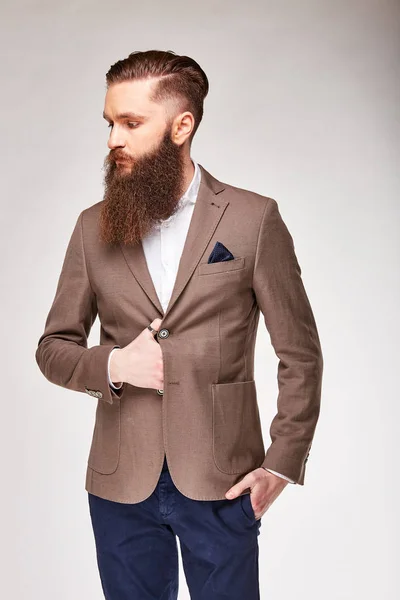 Young bearded man posing in studio in light brown trendy blazer, white shirt and blue pants — Stock Photo, Image