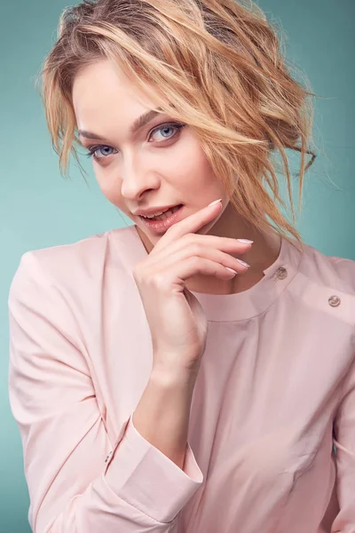 Portrait of young serious romantic blonde woman with big eyes and wavy hair, sexy smile, wearing light pink dress in studio on light turquoise background — Stok Foto