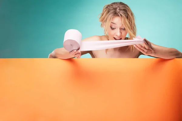 Joven hermosa mujer rubia sosteniendo rollo de papel higiénico con sonriente cara sorprendida en el estudio sobre fondo turquesa y hoja naranja — Foto de Stock