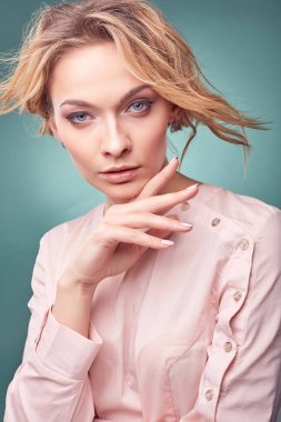 Portre Studio turkuaz arka plan ile hafif pembe elbise giyen genç seksi romantik sarışın kadın,