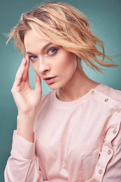 Портрет молодой сексуальной романтической блондинки, одетой в светло-розовое платье в студии с бирюзовым фоном — стоковое фото