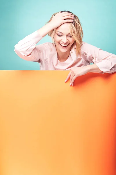 Joven linda mujer rubia riendo en el estudio con fondo turquesa y hoja naranja —  Fotos de Stock