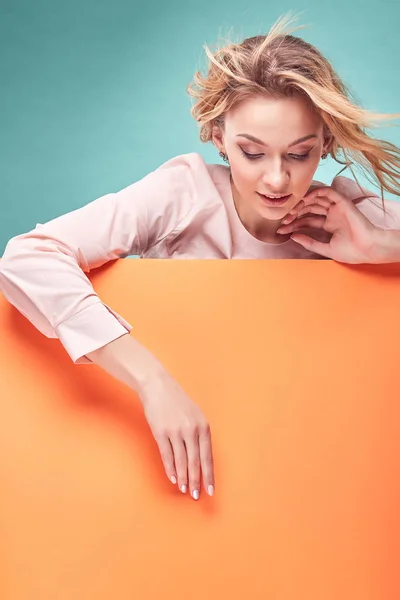 Retrato de la joven mujer rubia increíble mirando hacia abajo en el estudio con fondo turquesa y hoja de color naranja —  Fotos de Stock