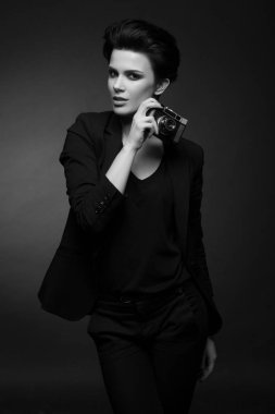 Eski fotoğraf makinesi siyah beyaz ellerini tutarak karanlık Studio'da poz genç ciddi inanılmaz kısa siyah saçlı giyen ile siyah kadın retro blazer