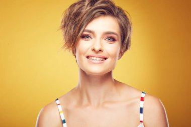Seksi genç güzel kadın modeli kısa ile portre portre Studio Sarı zemin üzerine poz ihale gülümsemeyle kameraya bakarak kumral, darmadağınık