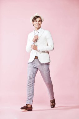 Beyaz ceket, beyaz gömlek, gri pantolon ve beyaz şapka Studio açık pembe renkli ile adım giyen genç güzel mutlu gülümseyen modern insan 