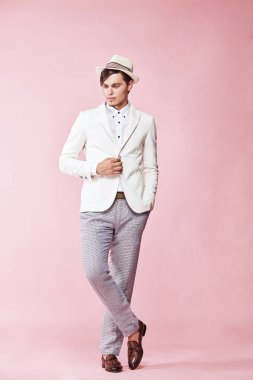 Beyaz ceket, beyaz gömlek, gri pantolon ve Studio açık pembe renkli ile poz ve aşağı bakıyor beyaz şapka giyen genç güzel mutlu ciddi modern insan