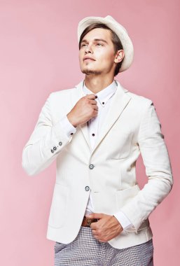 Beyaz ceket, beyaz gömlek, gri pantolon ve beyaz şapka Studio açık pembe renkli ile poz giyen genç güzel mutlu ciddi modern erkek modeli 