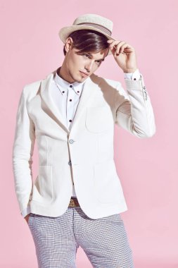 Beyaz ceket, beyaz gömlek, gri pantolon ve beyaz şapka Studio açık pembe renkli ile poz giyen genç yakışıklı ciddi modern erkek modeli