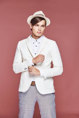 Beyaz ceket, beyaz gömlek, gri pantolon ve beyaz şapka Studio açık pembe renkli ile poz giyen genç yakışıklı ciddi modern erkek modeli 