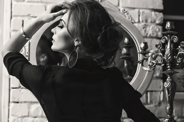 Siyah en iyi ve ışık etek giyen, lüks odada onu ve tablo, siyah ve beyaz şamdan beyaz ayna ile oturuyor ve çok şık ciddi olan kadın güzel makyaj, portresi