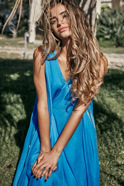 Csinos, fiatal nő modell a háttérben trópusi tájra lenyűgöző nyári hosszú kék ruhát viselt, hosszú, sötét hajjal portréja — Stock Fotó