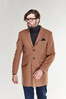 Sakal ve gözlük hafif kahverengi kaşmir palto ve koyu mavi pantolon Işık Studio poz ile çekici genç seksi erkek modeli 