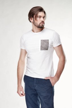 Sakal ve siyah saçlı beyaz tshirt gri cep ve koyu mavi pantolon Işık Studio ile poz ile çekici genç seksi erkek modeli