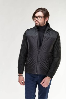 Sakal ve gözlük fermuar ve Işık Studio koyu mavi pantolon koyu yelek poz ile çekici genç seksi erkek modeli 